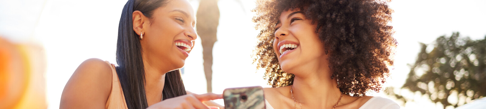 Friends laughing while holding a mobile phone.