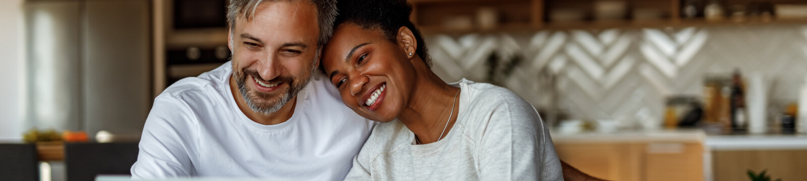 Couple sitting at kitchen table happy together.